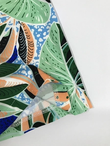 Detailed macro view of tropical leaf print fabric with precise double-needle hem stitching