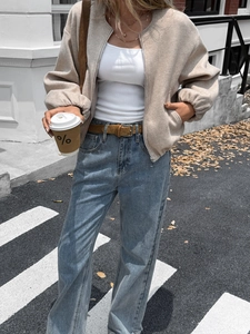Chic street style look featuring a beige cropped bomber jacket and blue straight jeans