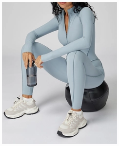 Dettaglio della tuta da yoga azzurra con cerniera e sneakers coordinate per fitness
