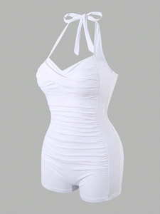 Detail of white halter neck one-piece swimsuit featuring ruched tummy control and boy-leg cut