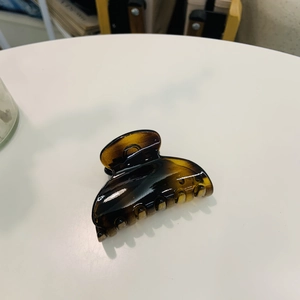 Close-up of tortoise shell heart hair claw clip with thick butterfly buckle on white desk