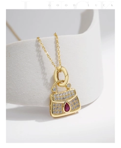Close-up of bag-shaped pendant necklace with red teardrop gem and sparkling zircons