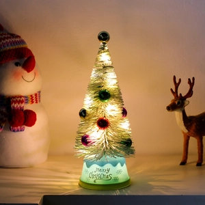 Close-up of mini cedar Christmas tree with colorful baubles and warm LED lighting base