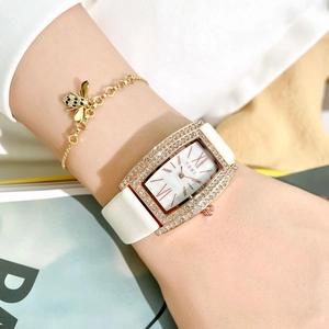 Close-up of gold rectangular quartz watch with crystal bezel and white leather strap