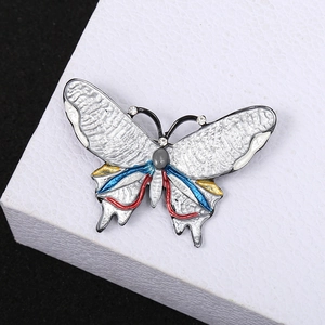 Spilla a farfalla in smalto con cristalli colorati e perla su un supporto premium