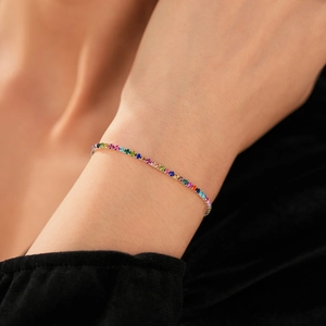 Dettaglio di un bracciale tennis con cristalli multicolori indossato con eleganza