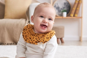 Detail of soft cotton baby bib with leopard print and ruffled gauze fabric texture