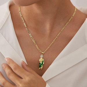 Close-up of Saint Jude gold necklace with green enamel on a figaro chain on a model