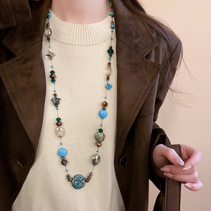 Detail of bohemian layered necklace with artificial stone beads and a metal butterfly charm