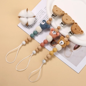 Three crochet bear pacifier clips in blue, pink and yellow with wooden beads and clips