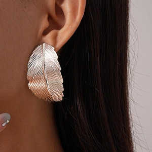Close-up of metallic silver leaf earrings featuring intricate vein textures on a model