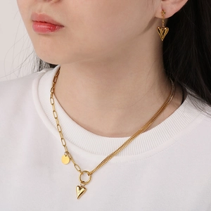 Golden heart jewelry set with layered necklace and matching earrings on model