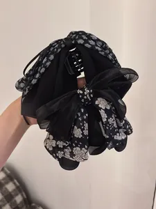 Detail showing layers of floral chiffon and mesh fabric on a ponytail hair claw clip
