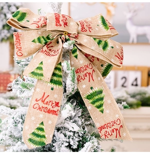 Detail of burlap Christmas bow with Merry Christmas text on a snow-covered tree