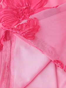 Gros plan sur un tissu rose en mesh et satin avec broderies florales et coutures nettes