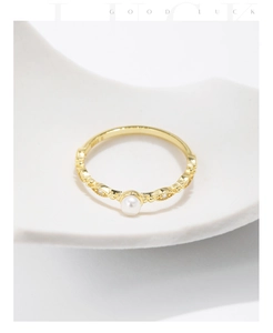 Close-up of vintage gold ring with a white pearl and sparkling zircons on white pedestal