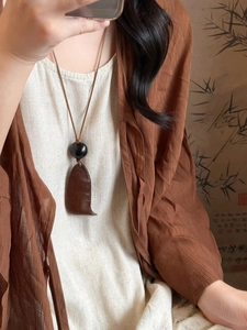 Gros plan d'un collier vintage avec pendentif en bois irrégulier porté par un mannequin