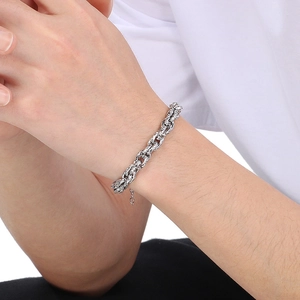 Gros plan d'un bracelet gourmette tressé en argent avec des maillons épais au poignet