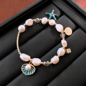 Détails de ce bracelet doré avec perles d'eau douce et breloques étoile de mer
