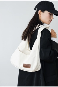 Detail of white corduroy shoulder bag showing vertical ribbed texture and leather logo tag