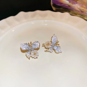 Boucles d'oreilles papillon dorées avec cristaux bleus et fleurs de nacre sur plateau