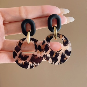 Macro detail of leopard print acrylic hoop earrings with a matte black oval top link