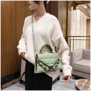 Detail of light green quilted shoulder bag featuring a black chain and triangle flap cover