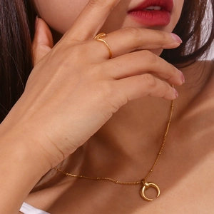 Close-up of minimalist 18K gold plated crescent moon necklace and wave ring on model