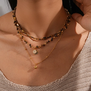 Detail of 18k gold plated layered necklace with tiger eye beads and sun pendant