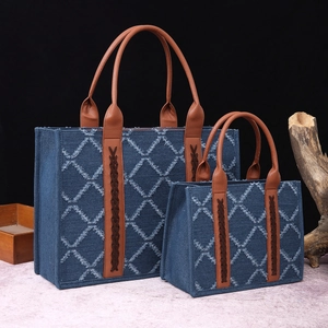 Detail view of denim tote bag set with white diamond patterns and woven leather straps