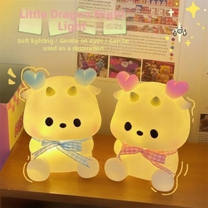 Macro shot of cute cartoon dragon night lights with velvet bows on a wooden desk