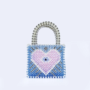 Detail of handmade beaded tote with pink heart pattern and evil eye motif decoration