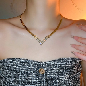 Close-up of gold-plated V-shaped necklace with diamonds on a model's neck