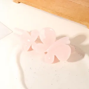 Close-up of a sweet light pink butterfly hair clip on a white textured display tray
