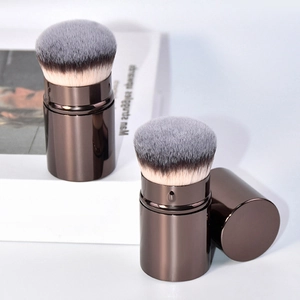 Macro detail of retractable dual-tone makeup brushes with metallic bronze handles