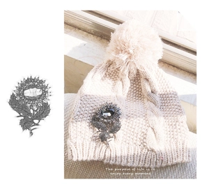 Detail of a sunflower brooch with dark crystals pinned on a beige knitted hat