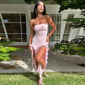 Pink strapless dress with tiered ruffles and side slit shown in sunny courtyard
