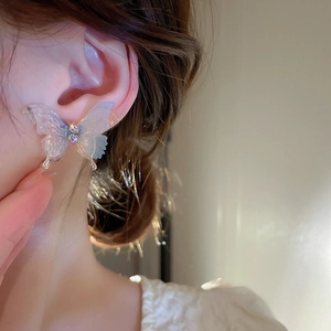Gros plan d'un mannequin portant des boucles d'oreilles papillon dégradées à cristaux