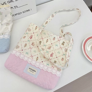 Detail of pink quilted tote bag with cute cartoon prints, lace trim, and heart patterns