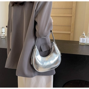 Silver metallic moon hobo bag worn by a model in a minimalist modern interior setting