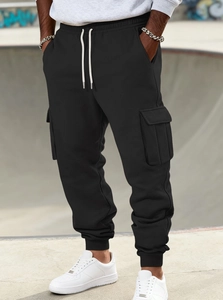 Detail view of black sweatpants featuring white contrast drawstrings and cargo flap pockets