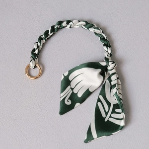 Detail of dark green silk scarf handle with gold metal ring for luxury handbags