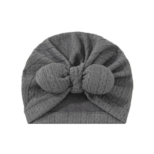 Close-up of dark grey baby turban hat with cable knit texture and large bow detail