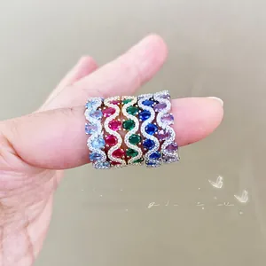 Close-up of stacked colorful gemstone eternity rings with wavy diamond accents