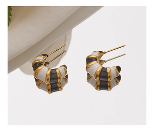 Detailed macro view of gold-plated bamboo texture earrings with black and white enamel