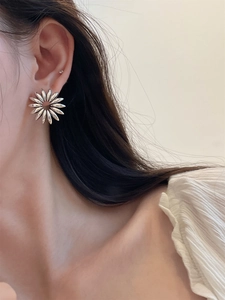 Close-up of large silver hollow flower earring worn on ear with minimalist style