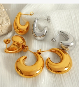 Close-up of chunky gold and silver crescent hoop earrings on elegant textured fabric