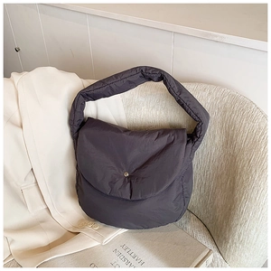 Detail of dark grey quilted shoulder bag featuring soft puffer texture and silver buckle