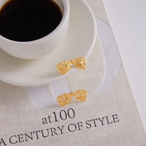 Détail macro de boucles d'oreilles nœud dorées avec texture en maille évidée sur un livre