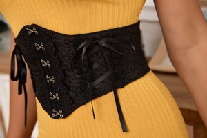 Detail of black lace corset belt featuring elegant floral patterns and ribbon ties